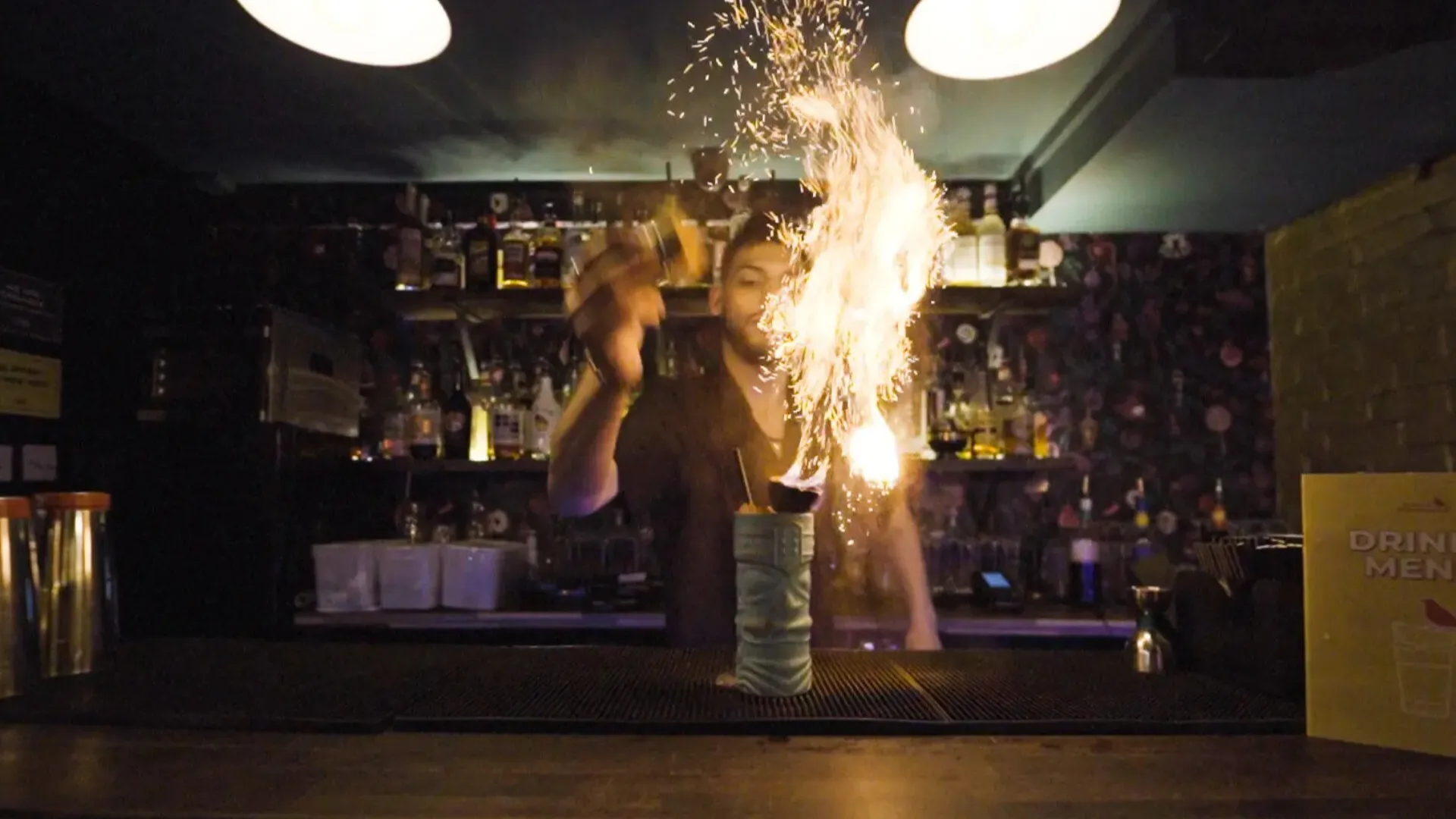 A firy show as the bartender garnishes a cocktail in a tiki glass at the bar