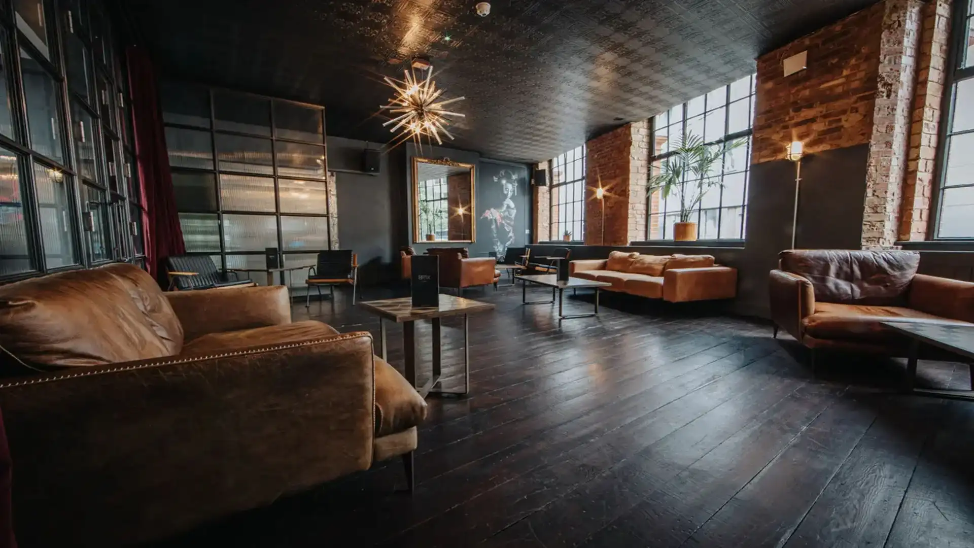 Black varnished floors, low comfy leather seating and industrial style tables with a cool light feature