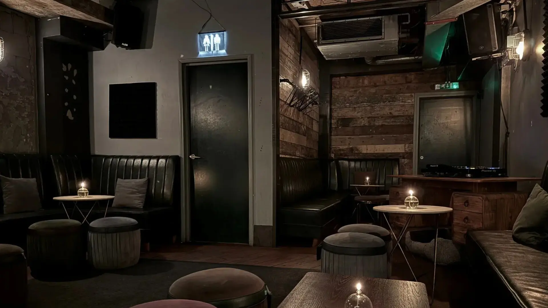 Secret back area next to DJ booth with rustic wood panels and Edison bulbs