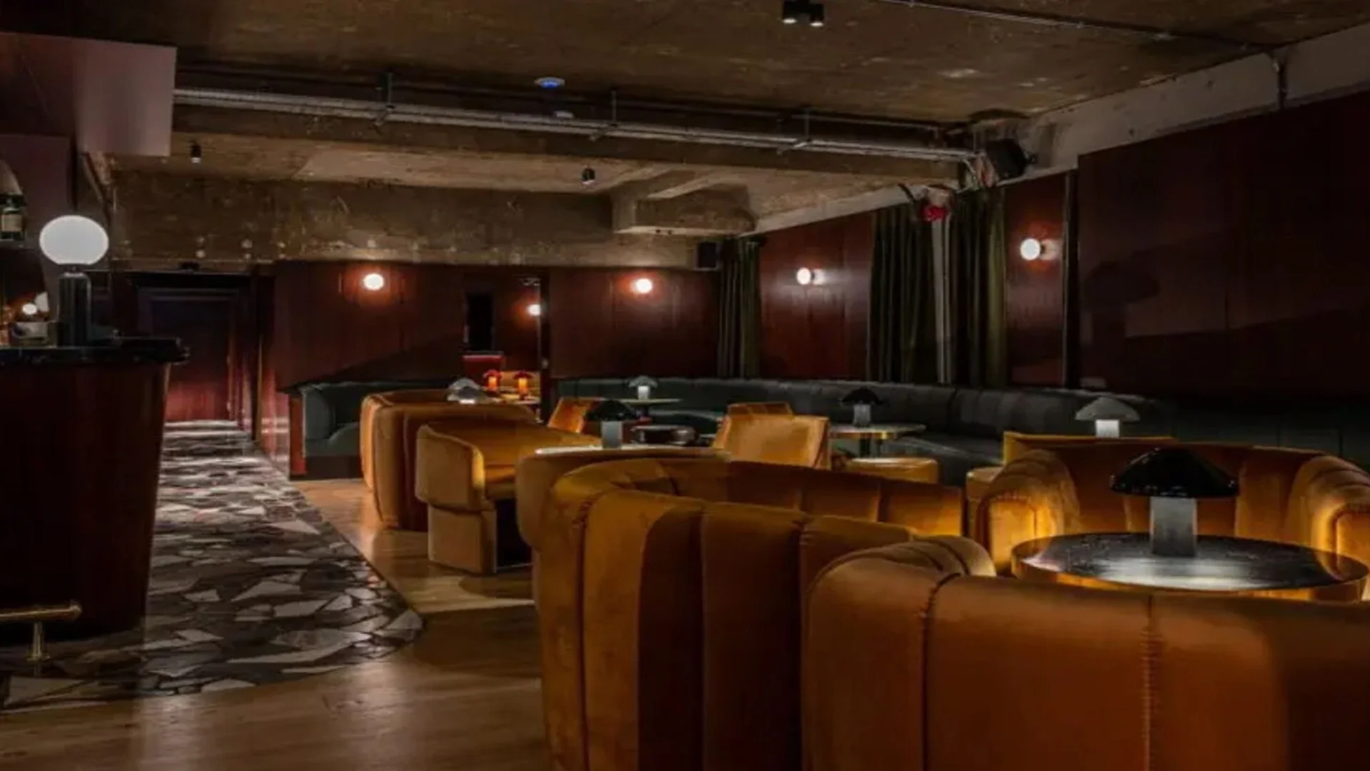 Large leather arm chairs, velvet green banquette seating and dimly lit purple walls