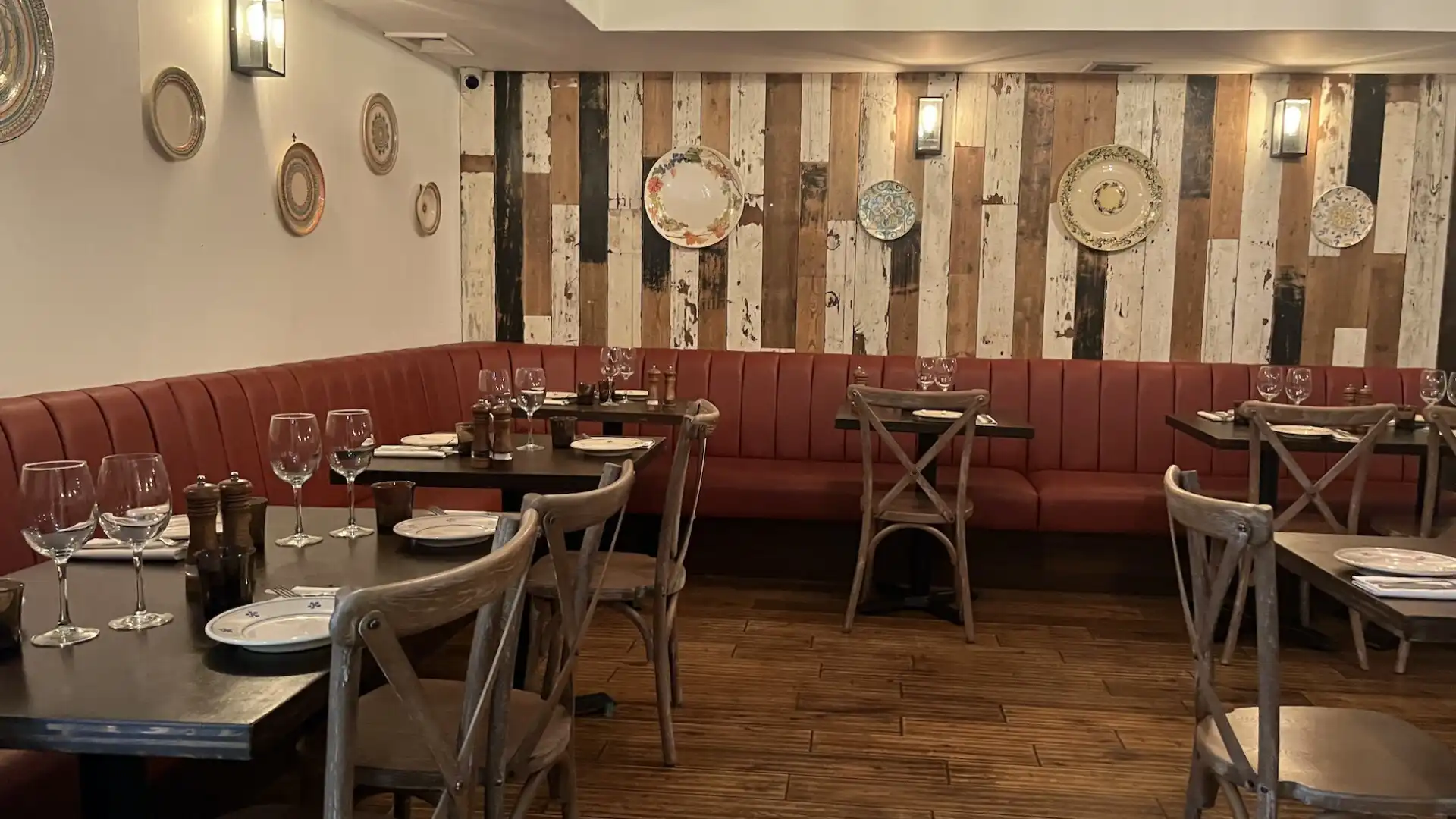 Mixed coloured, rough wood boards line the walls with Italian Nonna style plates