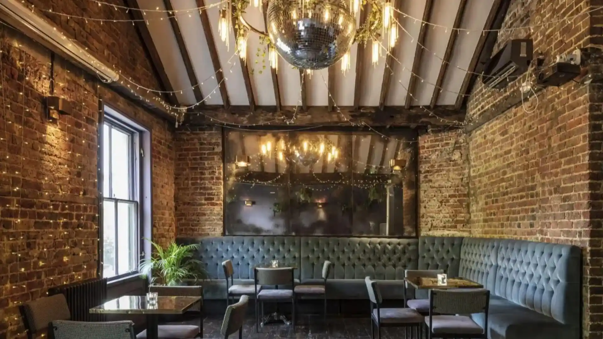 Tempered mirrored walls, exposed beams and a large disco ball above a turquoise banquette