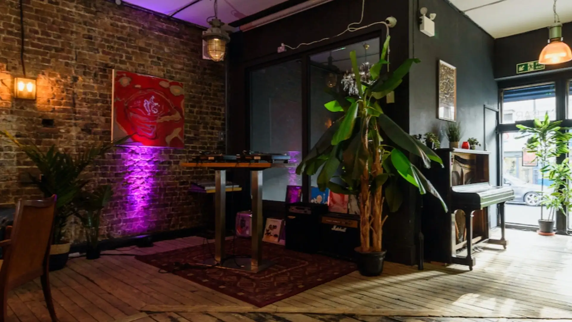 A DJ booth inside the glassed front of the venue with a Persian style rug